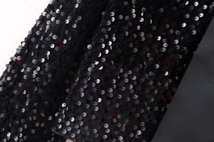 Macro detail of glossy black sequins and ribbing tape on high-density elegant fabric