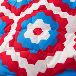 Detail of red white and blue geometric patterns with curved quilting stitches on the jacket