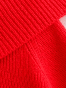 Close-up of bright red ribbed knit fabric detail and precision stitching on sweater