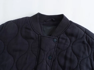 Detail of Y2K wave-quilted jacket featuring ribbed collar and dark snap buttons