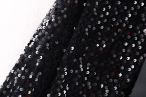 Macro detail of black sequin fabric with reflective texture for fashion evening wear