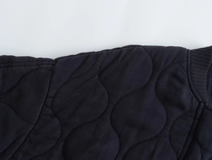 Macro view of wave quilted pattern and ribbed knit cuffs on navy blue bomber jacket