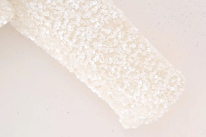 Vue détaillée de sequins ivoire brillants sur un haut ajusté Y2K à manches longues