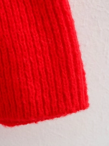 Macro shot of bright red sweater knit fabric with distinct vertical ribbed texture details