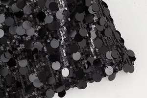 Vue macro détaillée de grandes paillettes noires sur tissu résille pour mini-jupe
