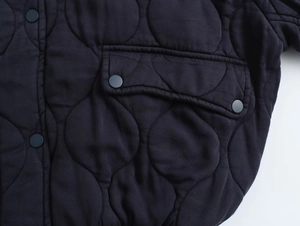 Detail of the unique circular quilted pattern and snap button on this Y2K bomber jacket