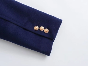 Close-up of navy wool jacket cuff featuring three embossed golden heraldic buttons