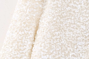 Détail de sequins nacrés blancs cousus en écailles sur le haut à manches longues de style Y2K