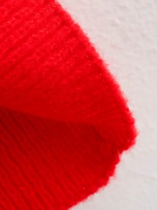 Macro detail of red knitted fabric texture with soft wool-like fibers on a white surface