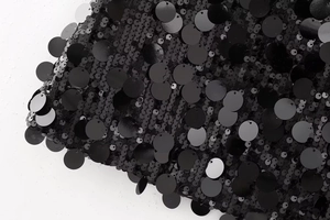Gros plan du tissu noir à paillettes avec des sequins ronds suspendus scintillants