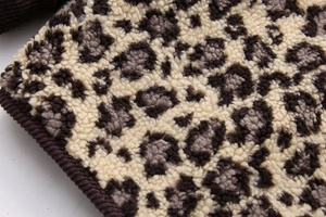 Detailed macro view of soft leopard print plush fabric with brown corduroy edge binding