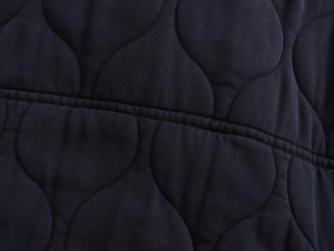 Close-up of navy blue onion-quilted fabric detail on a padded bomber jacket