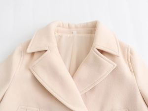 Macro detail of beige wool coat lapels showing premium fabric and double-breasted collar