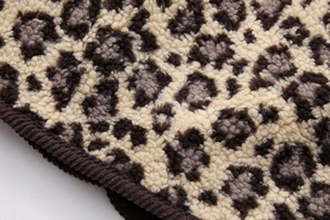 Close-up of thick leopard print plush fabric showing soft texture and edge binding