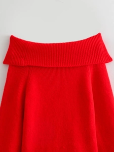 Detailed close-up of thick knitted red off-the-shoulder sweater texture and neckline