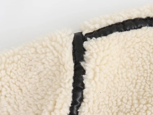 Détail de la matière sherpa avec liseré en cuir noir et finitions de couture précises