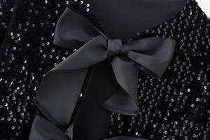 Détail d'un haut à paillettes noires avec un grand nœud décoratif en ruban gros-grain