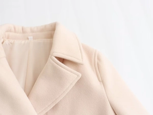 Detail view of cream wool coat featuring a notched lapel and smooth interior lining