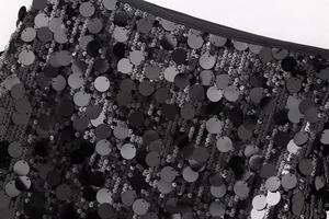 Détail macro de paillettes noires brillantes cousues sur la mini-jupe Y2K