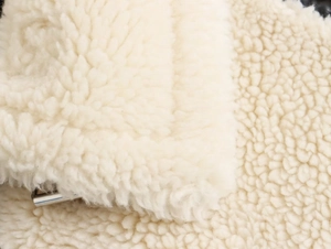 Détail de la texture pelucheuse crème avec fermeture éclair métallique sur une veste d'hiver