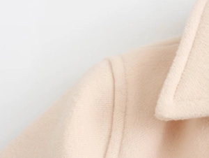 Detail shot of high-quality wool blend fabric and seam stitching on beige coat