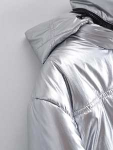 Détail de la veste argentée à capuche avec surpiqûres horizontales et fermeture éclair noire