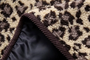 Detailed close-up of leopard print faux fur texture with brown corduroy piping