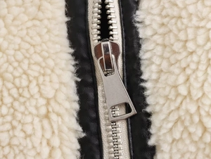 Détail de la veste en laine d'agneau avec garniture en similicuir noir et fermeture éclair