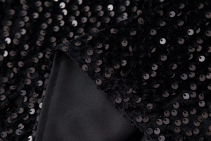 Close-up detail of shimmering black sequins on high-quality fabric of women top