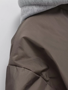 Detailed close-up showing brown woven fabric and grey knit hood stitching on winter jacket