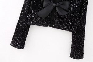 Détail du grand nœud en satin noir et des paillettes brillantes sur le haut court Y2K