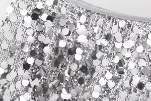 Vue macro détaillée de grandes paillettes argentées cousues sur tissu en maille blanche