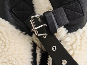 Détail de la veste en cuir noir avec doublure en mouton et boucle métallique stylée