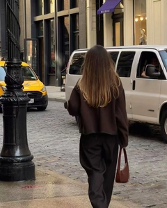 Street view of a woman wearing a dark brown oversized top and black wide-leg trousers
