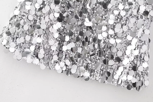 Gros plan de paillettes argentées sur maille blanche montrant la texture métallique
