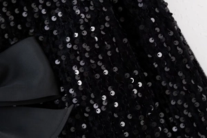 Détail macro du tissu à paillettes noires avec nœud en gros-grain sur haut Y2K