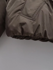 Detailed view of elastic hem and stitching on an olive green winter padded jacket