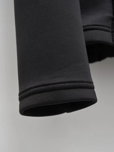 Gros plan détaillé des poignets côtelés et coutures sur la veste noire Y2K