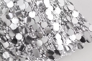 Gros plan de paillettes argentées cousues sur du mesh blanc pour une mini-jupe style Y2K