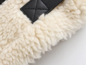 Détail du tissu sherpa blanc et sangle en cuir noir avec couture en croix renforcée