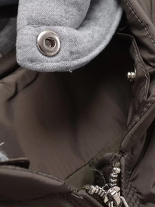 Close-up of metal snap buttons and zipper on the mixed-material hooded winter jacket