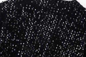 Détail rapproché des paillettes noires scintillantes sur un haut Y2K ajusté à manches longues
