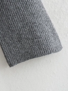 Detailed macro view of the grey ribbed knit texture and fine stitching on the sweater cuff