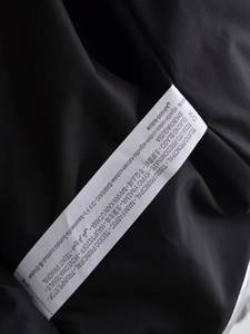 Gros plan sur l'étiquette d'entretien 100% coton d'une veste noire style Y2K