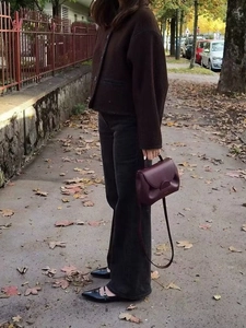 Women's burgundy leather crossbody bag styled with autumn streetwear and casual wool jacket
