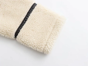 Gros plan sur la peau de mouton crème et le liseré en cuir noir d'une veste style Y2K