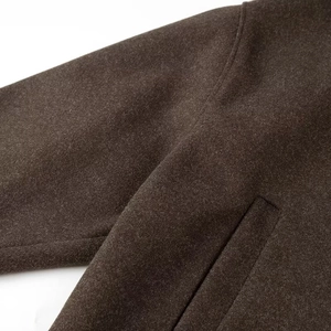 Detail shot of heavy wool fabric texture and shoulder stitching on a brown jacket