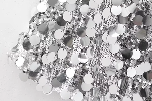 Détail macro de paillettes argentées miroirs cousues sur un tissu en maille respirant