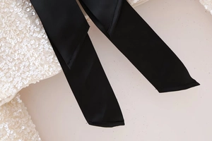 Close-up of sparkling sequin fabric with a contrasting black grosgrain ribbon bow tie