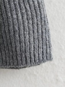 Detailed close-up of dark grey ribbed knit sweater cuff showing soft wool texture